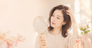 手鏡で髪を見ながら白髪を気にする30〜40代女性