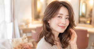 ゆるやかなウェーブパーマの髪をやさしく触る30〜40代女性