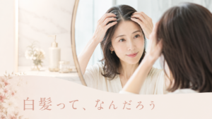 鏡の前で分け目の白髪を見る女性